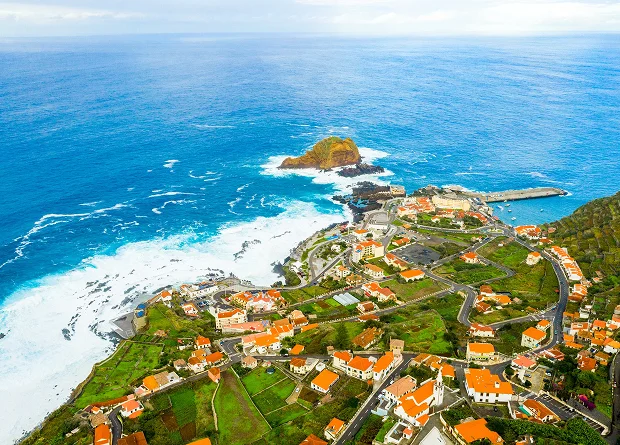 Aerial view of the coastal village of Porto Moniz, Madeira, famous for its volcanic natural swimming pools and rugged coastline.